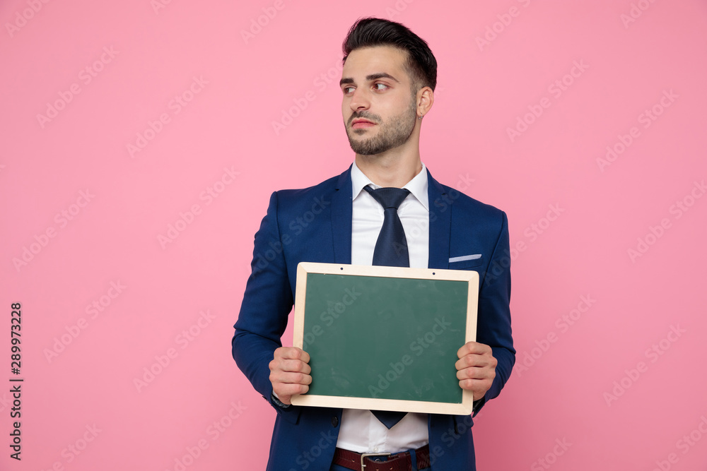 attractive young man holding an empty board on pink background attractive young man holding an empty board on pink background