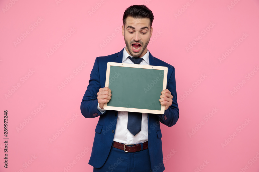 smart casual man holding an empty board on pink background smart casual man holding an empty board on pink background
