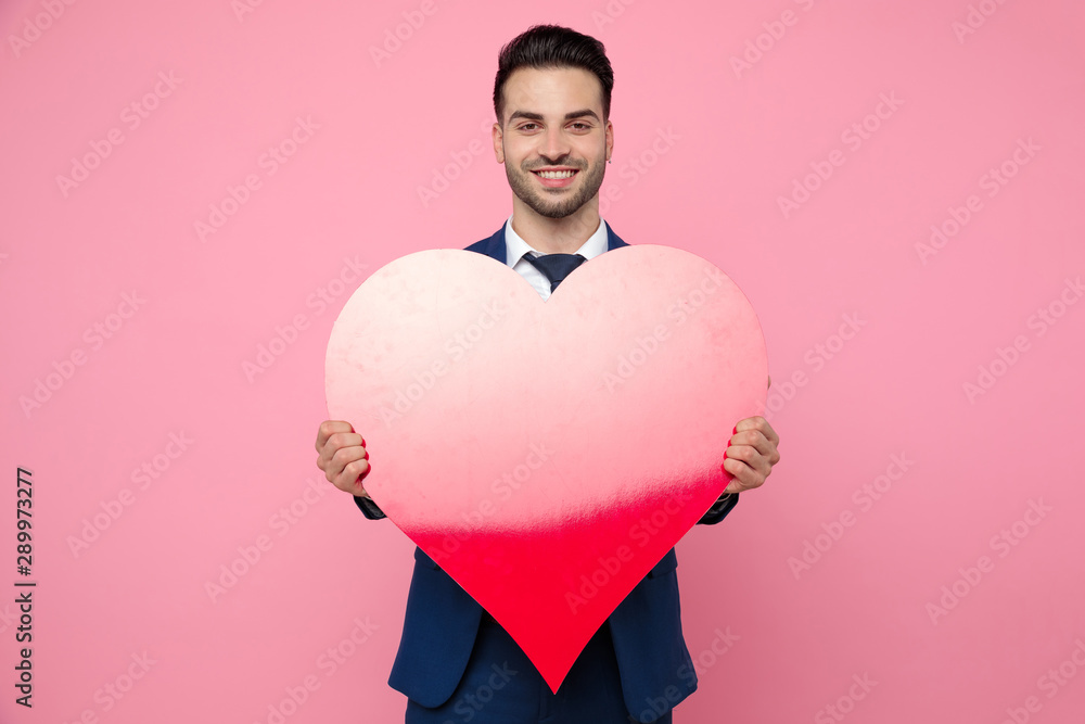 handsome man holding a heart on pink background in studio handsome man holding a heart on pink background in studio