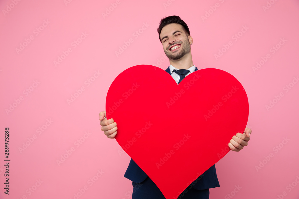 smart casual man holding red heart on pink background smart casual man holding red heart on pink background