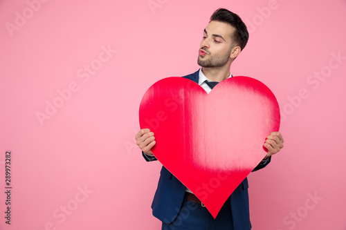 handsome young man holding red heart on pink background © Viorel Sima