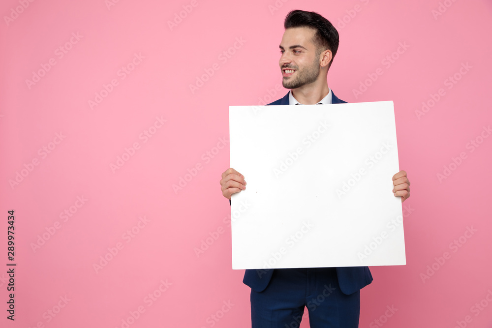 attractive young man holding empty board on pink background attractive young man holding empty board on pink background
