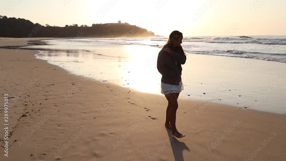 Pan up of young woman walking on the beach at sunrise in Australia Pan up of young woman walking on the beach at sunrise in Australia