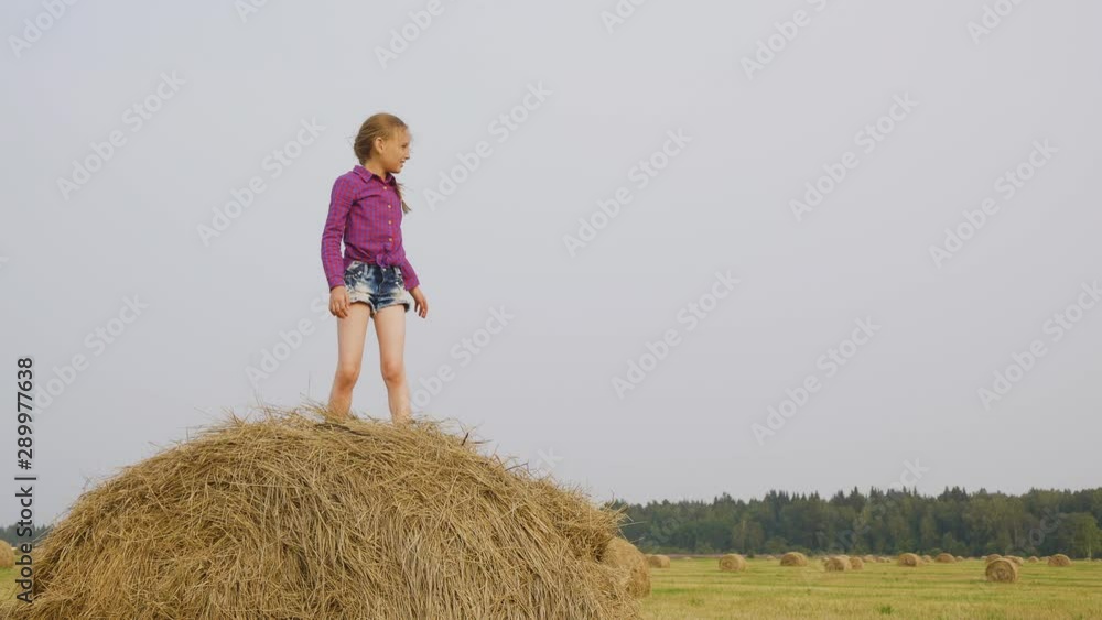Children playing on haystack. Cute happy girl dancing and jumping on haystack while cheerful boy running on field. Childhood concept Children playing on haystack. Cute happy girl dancing and jumping on haystack while cheerful boy running on field. Childhood concept