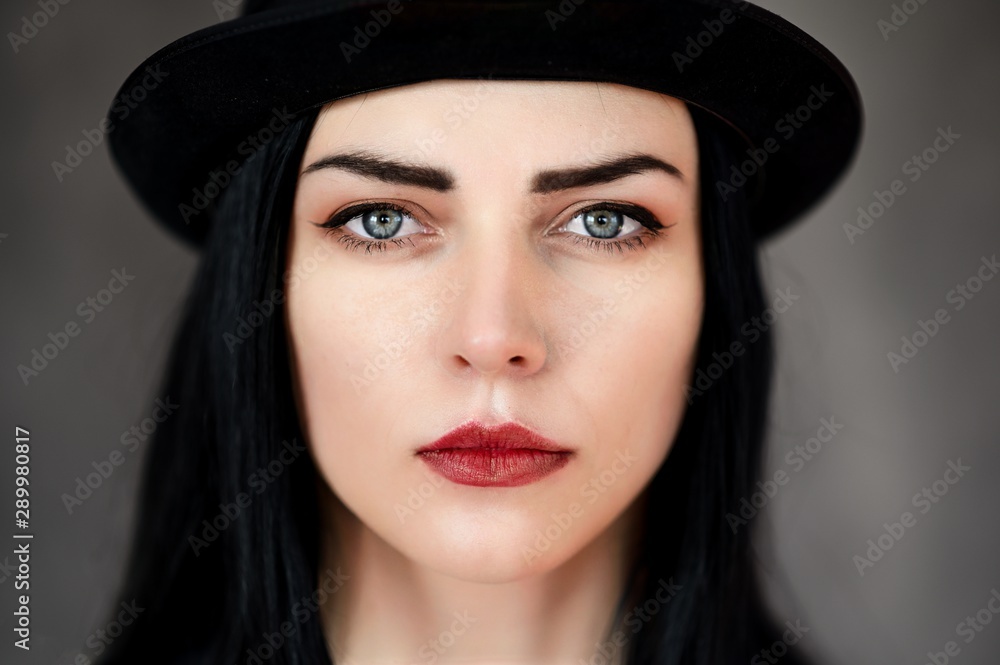 Creative Concept portrait of a pretty brunette girl with long black hair on a gray background in the studio. Cosmetics, facial skin, art. Creative Concept portrait of a pretty brunette girl with long black hair on a gray background in the studio. Cosmetics, facial skin, art.