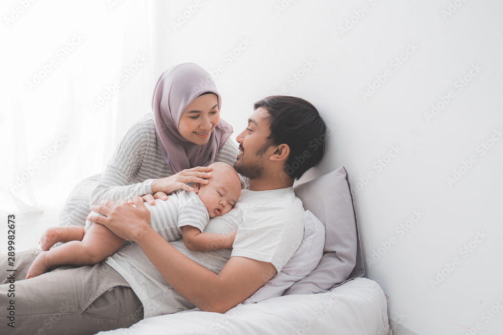 lovely muslim couple with their infant baby boy in bedroom lovely muslim couple with their infant baby boy in bedroom