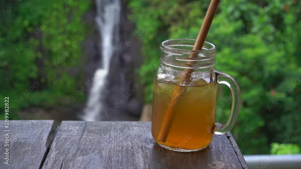 Slowmotion shot of a young woman in a beautiful cafe with an epic view on a canyon and waterfall drinks tea with ice. Travell to Bali concept Slowmotion shot of a young woman in a beautiful cafe with an epic view on a canyon and waterfall drinks tea with ice. Travell to Bali concept