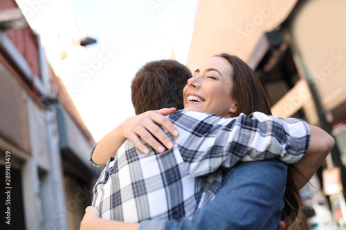 Joyful couple hugging in the street after meeting © Antonioguillem