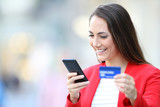 Happy woman buying on line with phone and credit card
