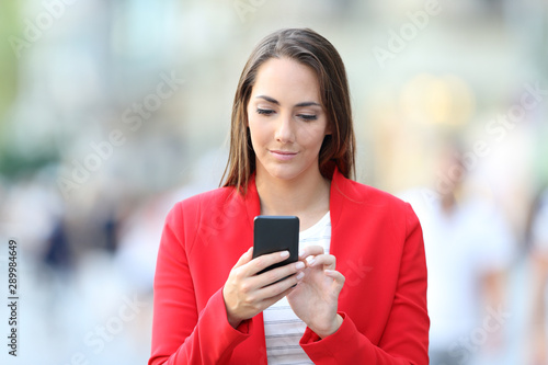 Front view of serious woman in red using phone