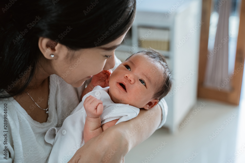 Close up loving mother kissing baby daughter in the house Close up loving mother kissing baby daughter in the house