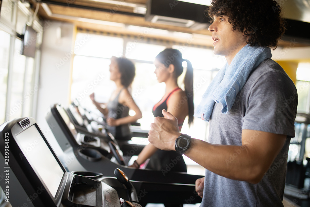 Group of young people running on treadmills in modern sport gym Group of young people running on treadmills in modern sport gym