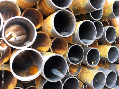 close-up of a pile of rusty metal pipes laying on the street