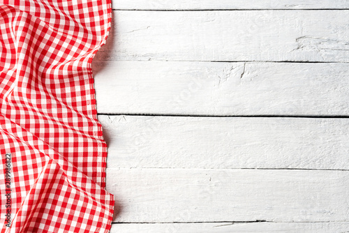 Red checkered tablecloth on white wooden table. Top view