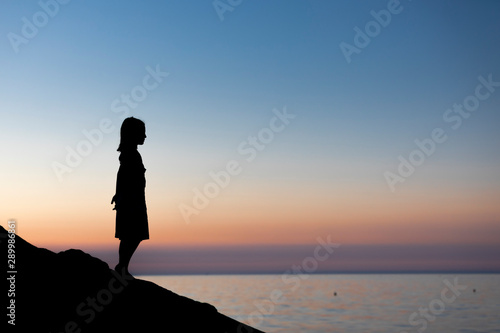 Silhouette di bambina che guarda il mare al tramonto