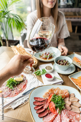 Date, man and woman Clink wine glasses. Beautiful young elegant woman in the restaurant with a wine glass. Dinner and a variety of dishes on the table. Italian cuisine