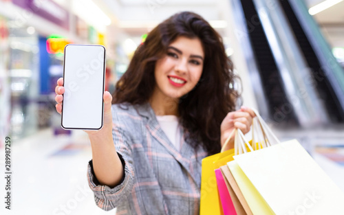 Girl showing cellphone after shopping in big mall