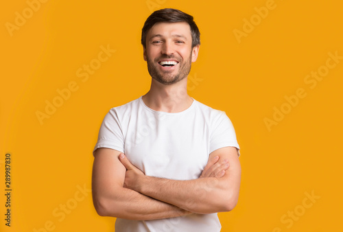 Happy Middle Aged Man Laughing Crossing Hands On Yellow Background