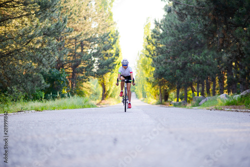 Young Woman Cyclist Riding Road Bicycle on the Free Road in the Forest at Hot Summer Day. Healthy Lifestyle Concept. © Maksym Protsenko