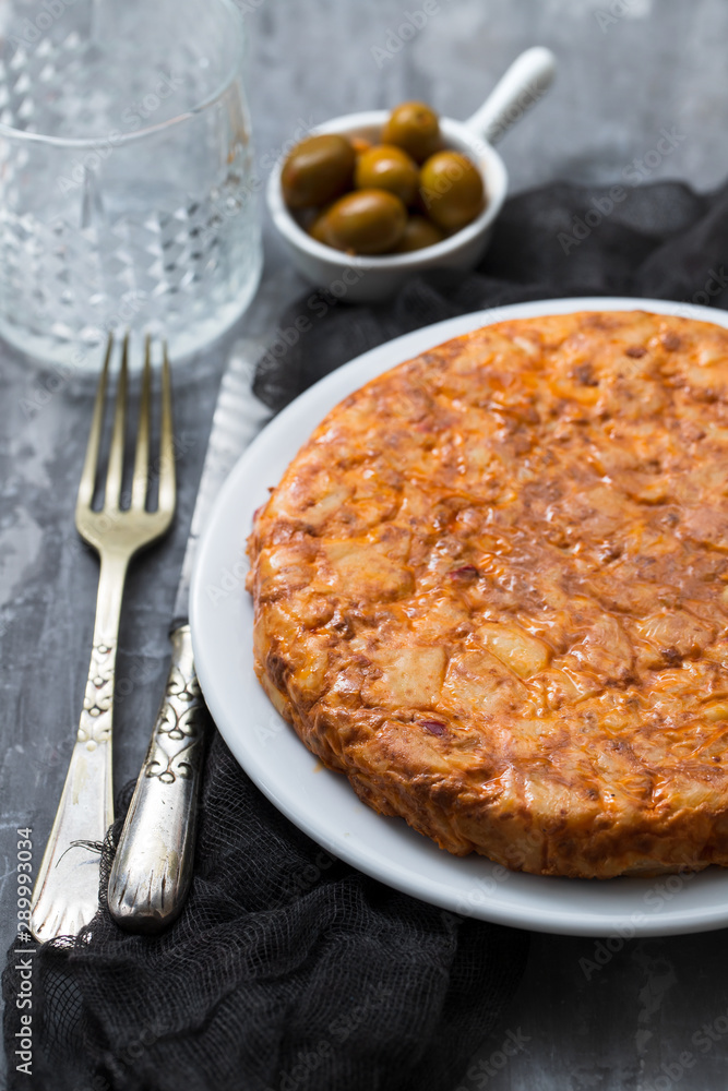 Traditional spanish food Tortilla with potato on white dish and olives in small bowl on ceramic background. Traditional spanish food Tortilla with potato on white dish and olives in small bowl on ceramic background.