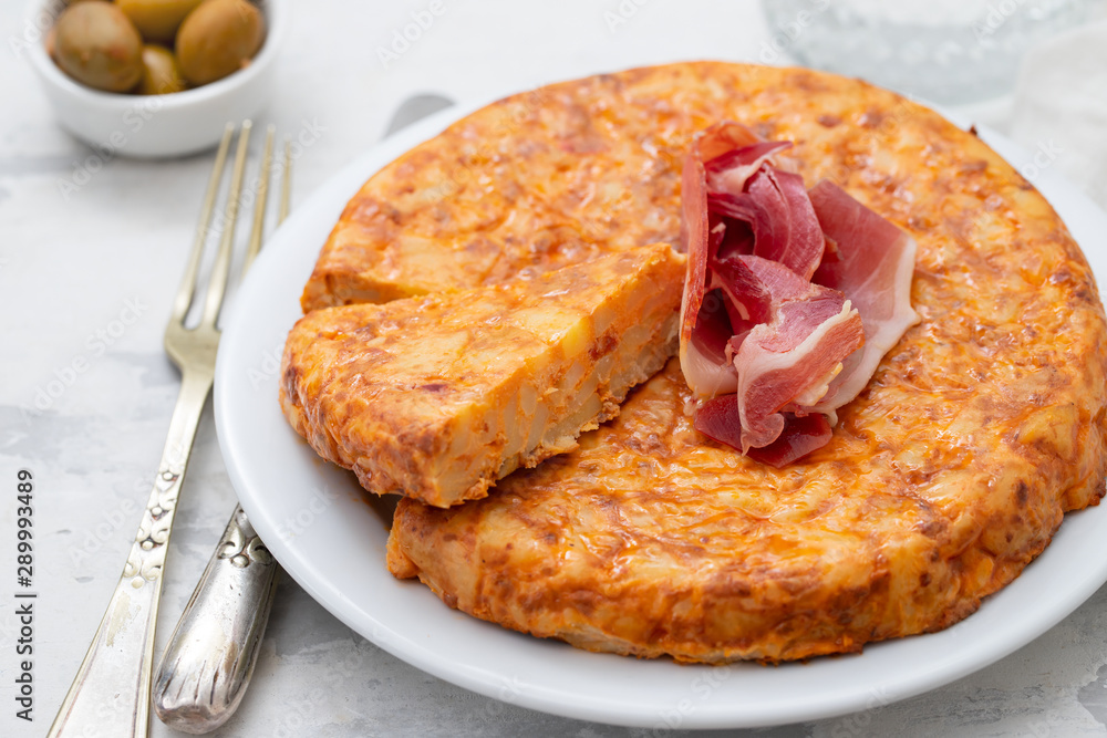 typical spanish food Tortilla with smoked meat and potato on white dish typical spanish food Tortilla with smoked meat and potato on white dish