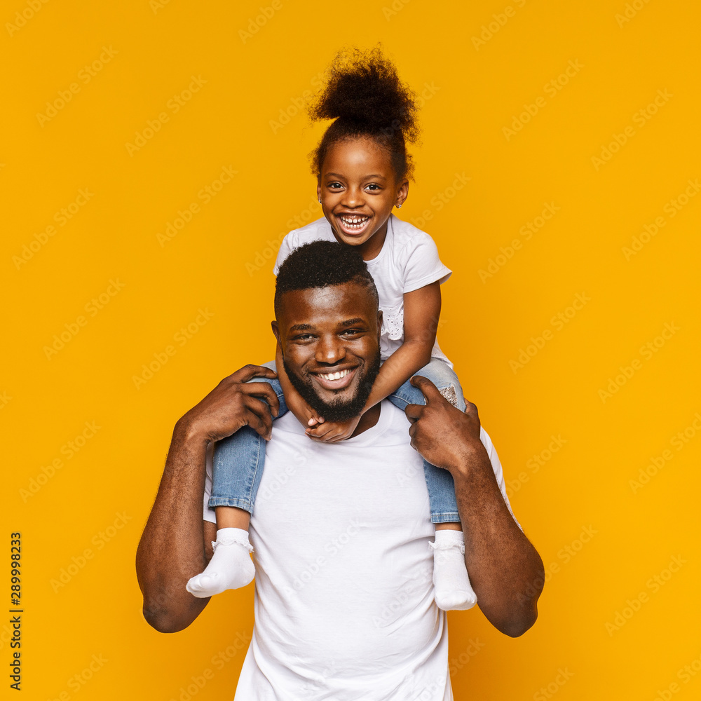 Millennial african father riding his little daughter on shoulders - obrazy, fototapety, plakaty 
