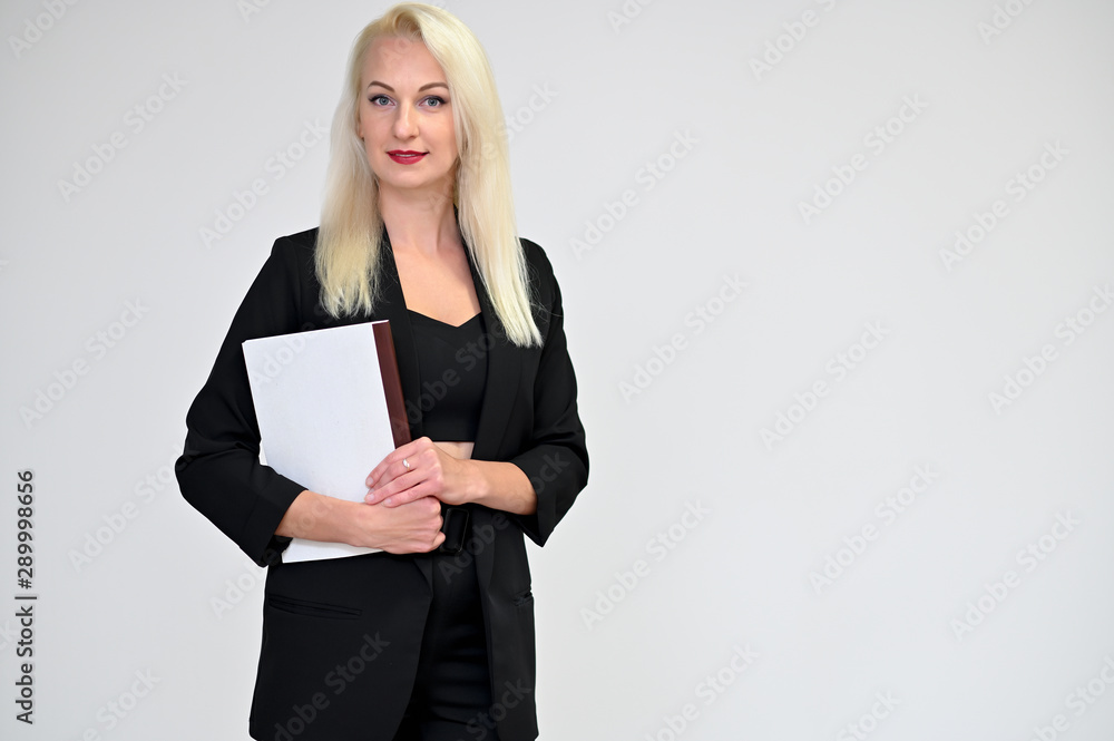 Concept portrait of a pretty young blonde woman with long beautiful hair in a black business suit with a folder in her hands on a white background in studio. Standing in different poses with a smile. Concept portrait of a pretty young blonde woman with long beautiful hair in a black business suit with a folder in her hands on a white background in studio. Standing in different poses with a smile.