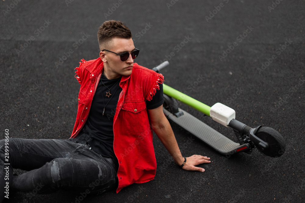 handsome young man wearing sunglasses sitting with bottles of red