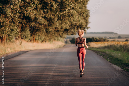 Young woman runner running on city bridge road © danilishina_30