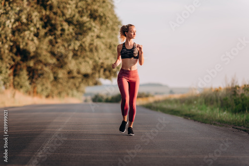 Young happy athletic woman in sport wear doing warming up training of run