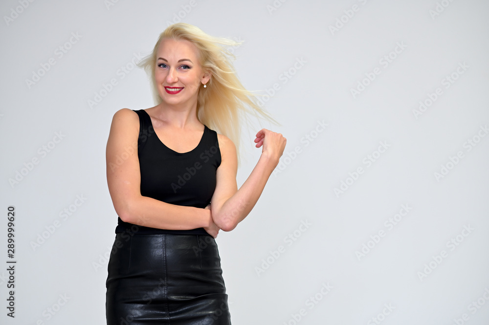 Concept portrait of a pretty young blonde woman with long beautiful hair in a black suit on a white background in studio. Standing in front of the camera in various poses with a smile. Concept portrait of a pretty young blonde woman with long beautiful hair in a black suit on a white background in studio. Standing in front of the camera in various poses with a smile.