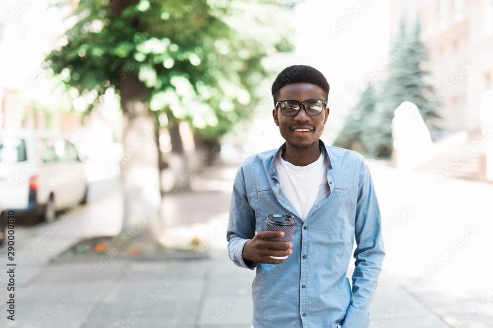 Portrait of happy young african man walking on the street with cup of coffee. Portrait of happy young african man walking on the street with cup of coffee.
