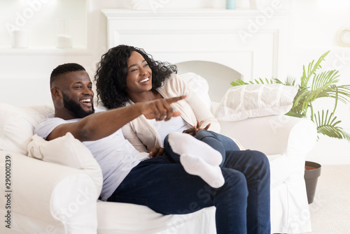 Watching Comedy Movie. Young African American Couple Resting On Sofa