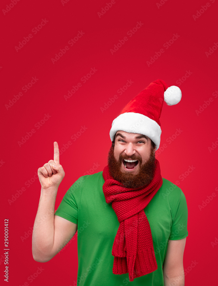 Excited man in Christmas hat pointing up Excited man in Christmas hat pointing up