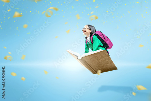 Asian cute girl with glasses and backpack sitting on the book flying