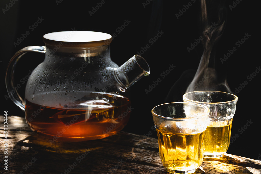 The steam from a cup or pot of coffee or tea on the old wood table and black background, Warm drinks make good healthy, Selective focus. The steam from a cup or pot of coffee or tea on the old wood table and black background, Warm drinks make good healthy, Selective focus.