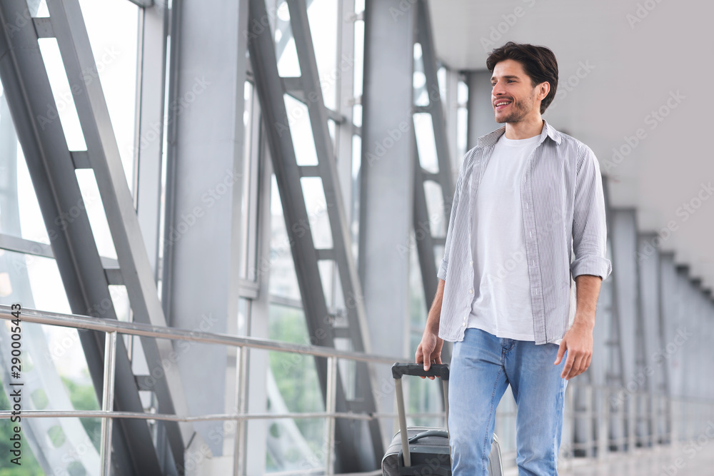 Millennial tourist with luggage in airport, enjoying future trip Millennial tourist with luggage in airport, enjoying future trip