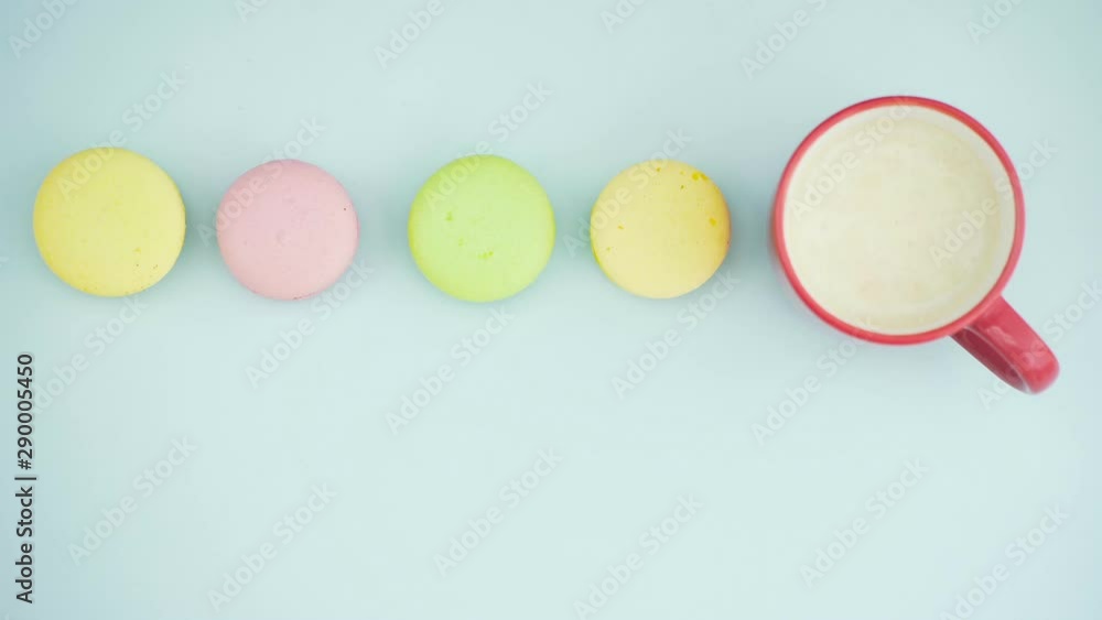 Macaroons or macaron on pastel blue surface with coffee in red cup. Macaroons or macaron on pastel blue surface with coffee in red cup.