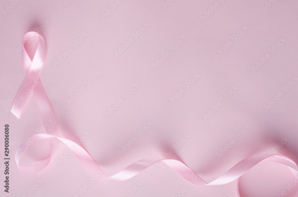 Top view of pink ribbon on the pink background, free space for design