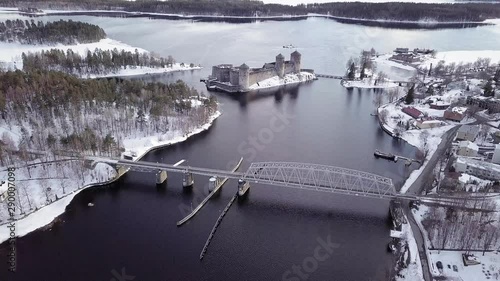 Medieval castle and railbus crossing a bridge over lake at Kyronsalmi strait in Savonlinna, Finland. photo