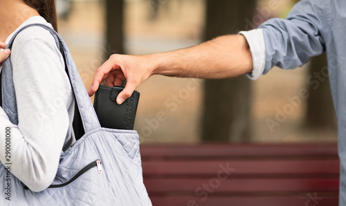Pickpocket thief stealing wallet from woman handbag photo