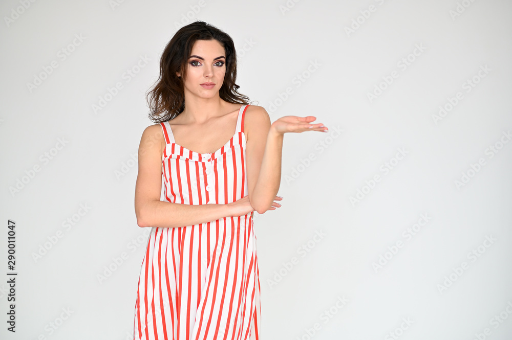 Concept photo portrait of a cute pretty beautiful brunette girl with excellent makeup in a striped dress on a white background. In different poses with emotions. Concept photo portrait of a cute pretty beautiful brunette girl with excellent makeup in a striped dress on a white background. In different poses with emotions.