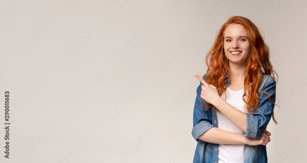 Cheerful Redhead Girl Pointing Finger Aside At Free Space Cheerful Redhead Girl Pointing Finger Aside At Free Space