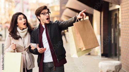 Guy pointing on shopwindow, walking and shopping outdoors