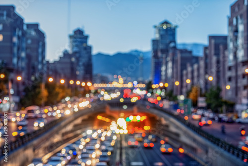 Blurred and Famous view of Tehran,Flow of traffic around Tohid Tunnel with Milad Tower and Alborz Mountains in Background, night cityscape concept