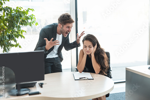 strict boss man swearing at depressed employee woman for bad work at the workplace looking angry