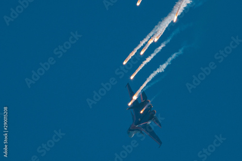 Fototapeta Naklejka Na Ścianę i Meble -  Modern jet fighter shooting fire flares rockets with sparks. Airplane deploying fire protection IRCM