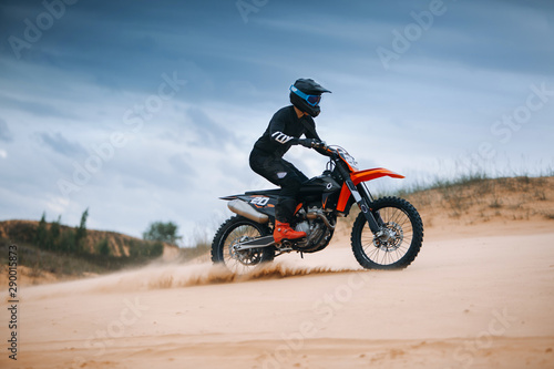 Motorcyclist on a cross-country motorcycle go fast at the dune