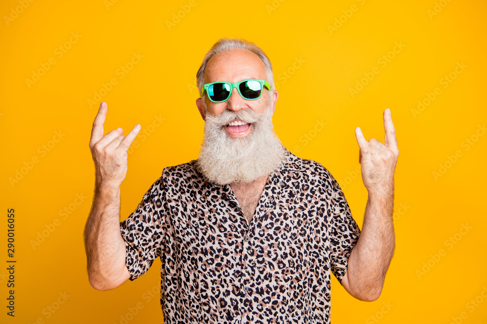 Portrait of cheerful funky funny old bearded man with eyewear eyeglasses  showing horns sign enjoy rock and rool party event wearing leopard print  shirt isolated over yellow background Stock Photo | Adobe