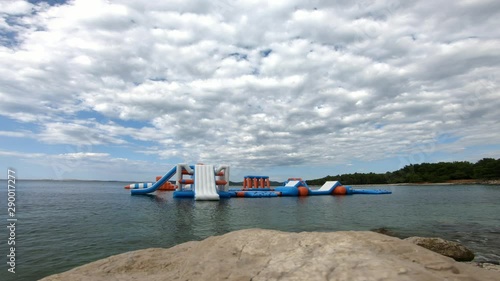 Early morning and an empty bouncy castle on water with white clouds andblue sky photo